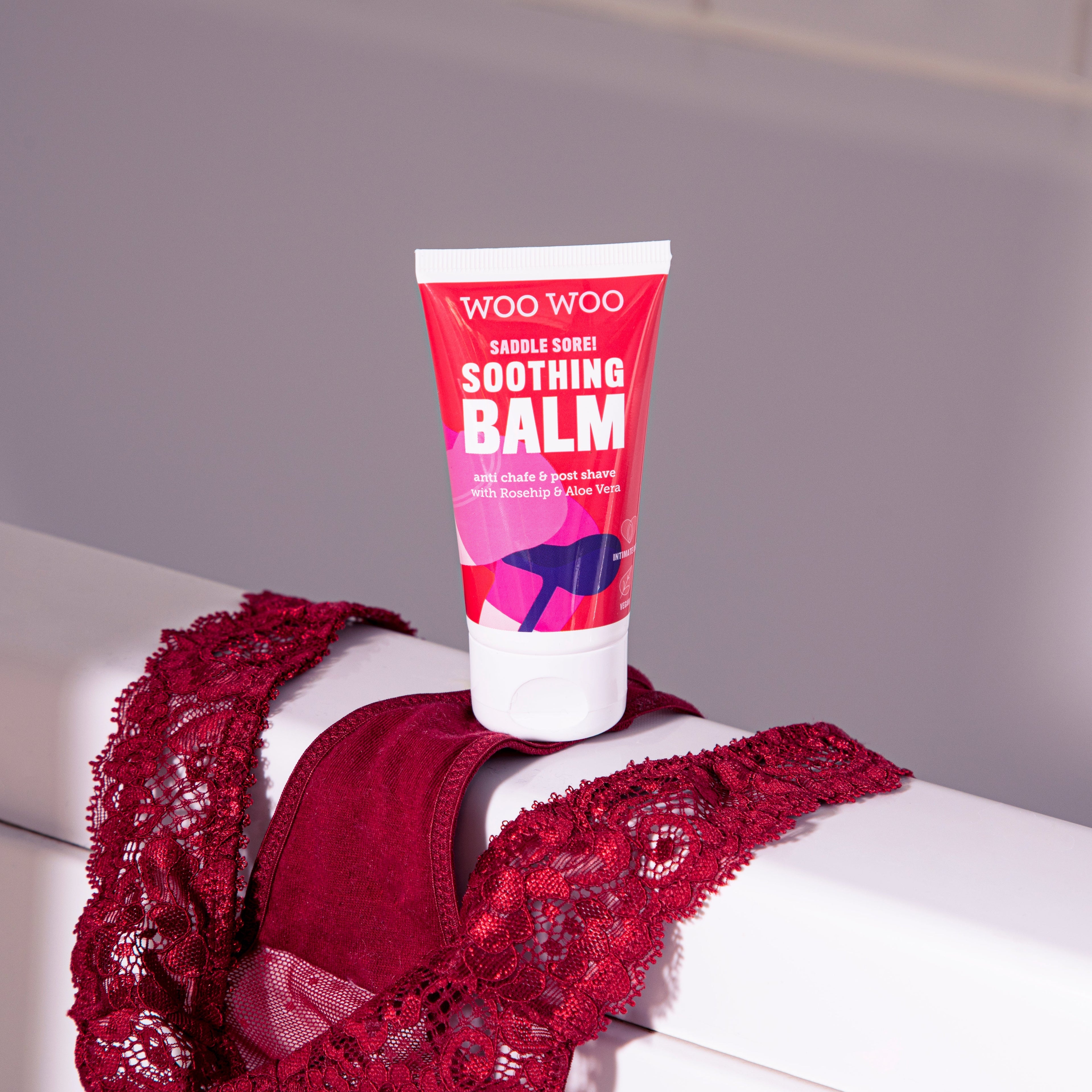 Tube of WooWoo Saddle Sore Soothing Balm with red lingerie background