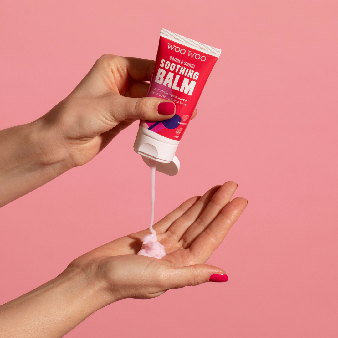 Tube of WooWoo soothing balm being poured into hand on pink background